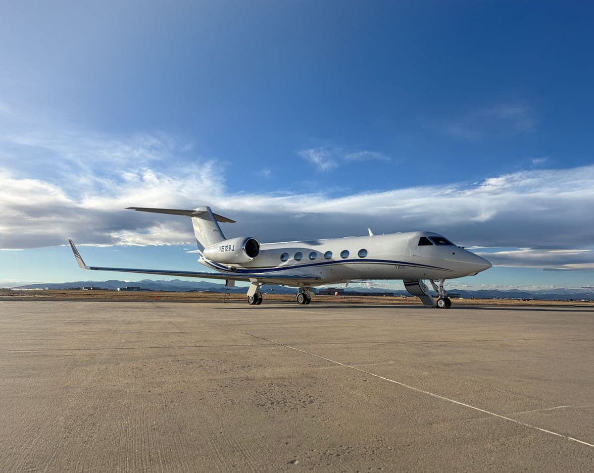 A Gulfstream jet is parked on the tarmac with a white and blue paint scheme.