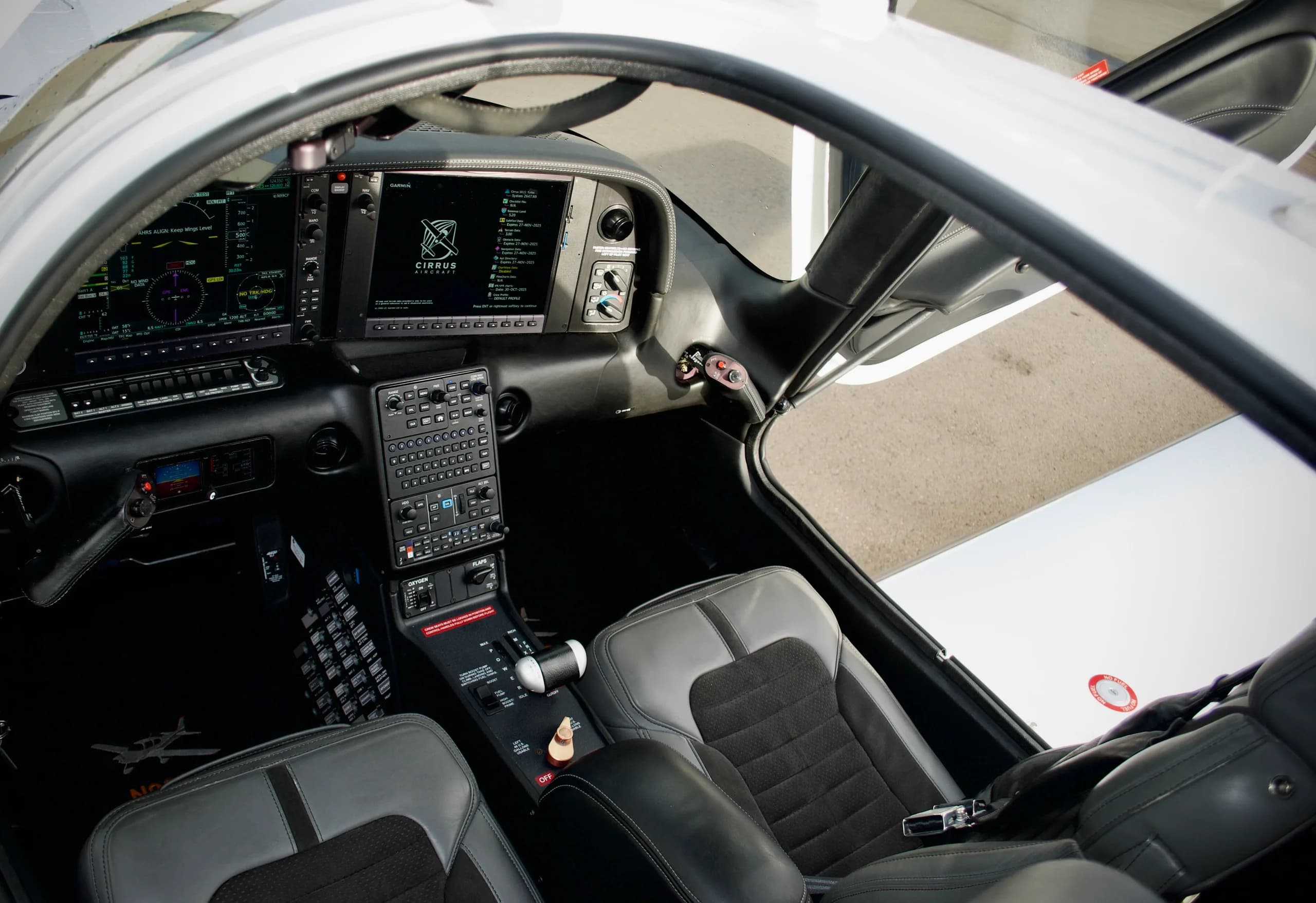 The cockpit of the Cirrus SR22T aircraft, featuring a modern glass panel display and gray seats.