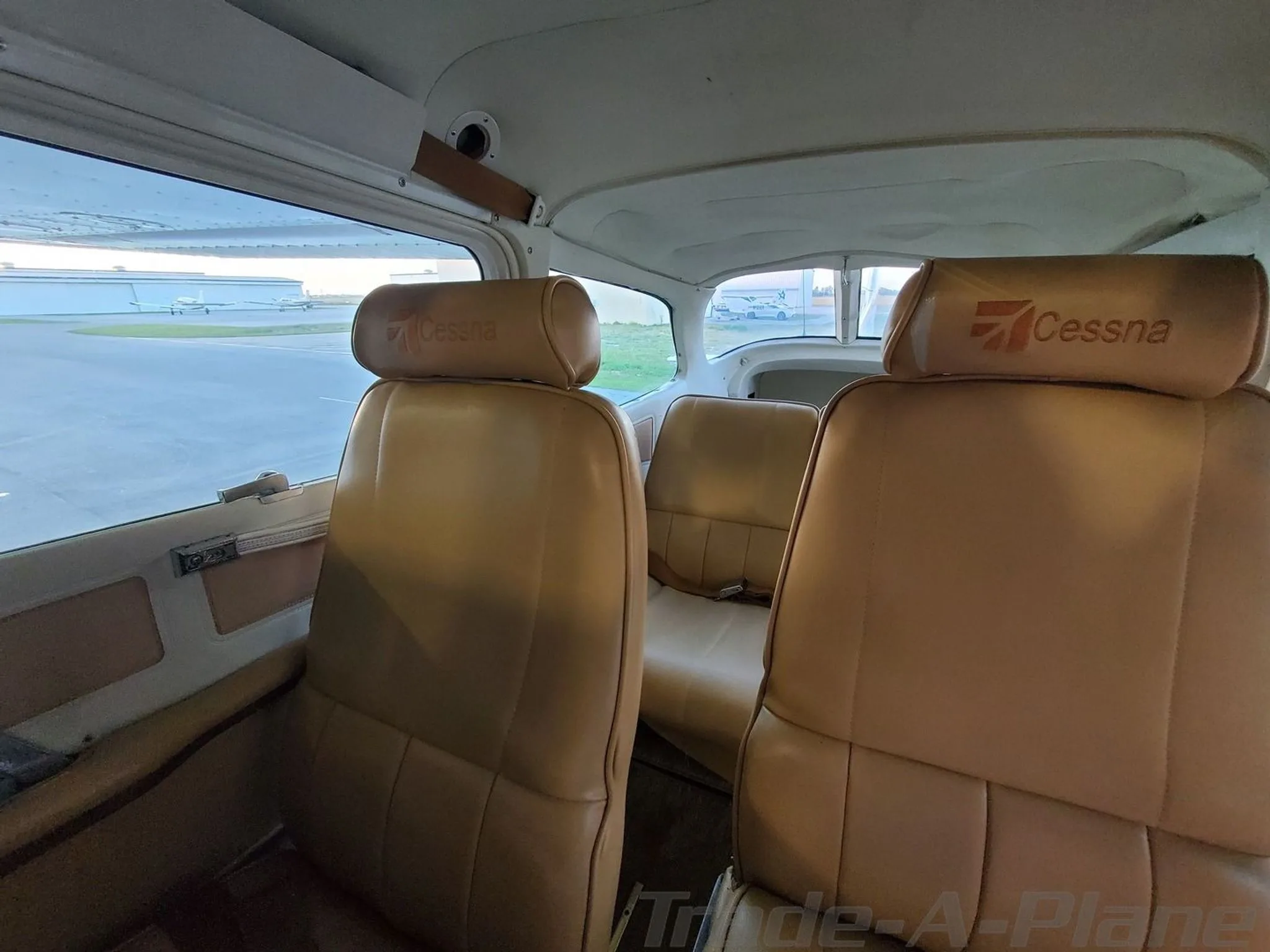 The tan leather rear seats of a Cessna Cutlass RG II cabin, with "Cessna" embossed on the headrests.