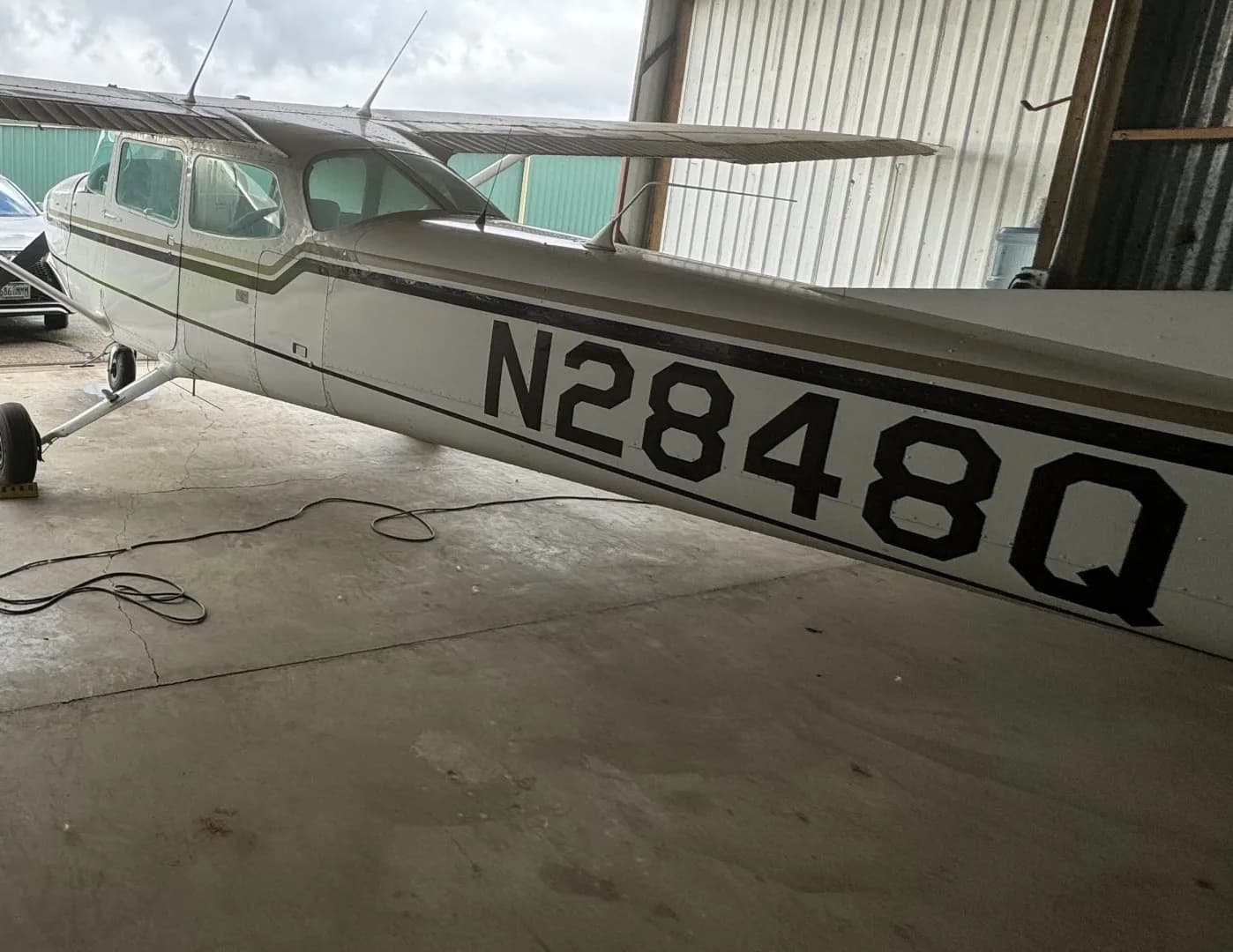 A white and gold Cessna aircraft, N2848Q, is parked inside a hangar, viewed from the front-right side.