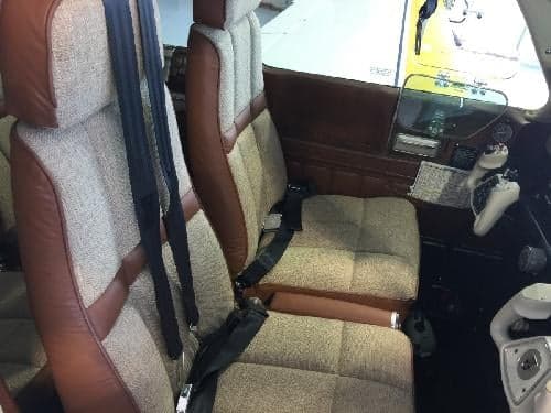 The interior of the aircraft features brown and tan seats with black seatbelts.