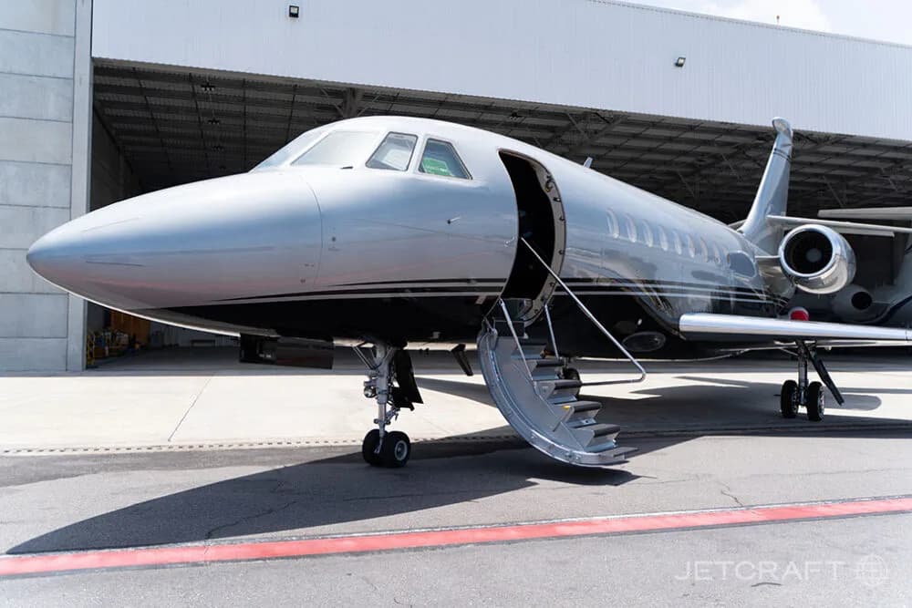 A silver and black business jet with its main entry door open, revealing the integrated airstairs.