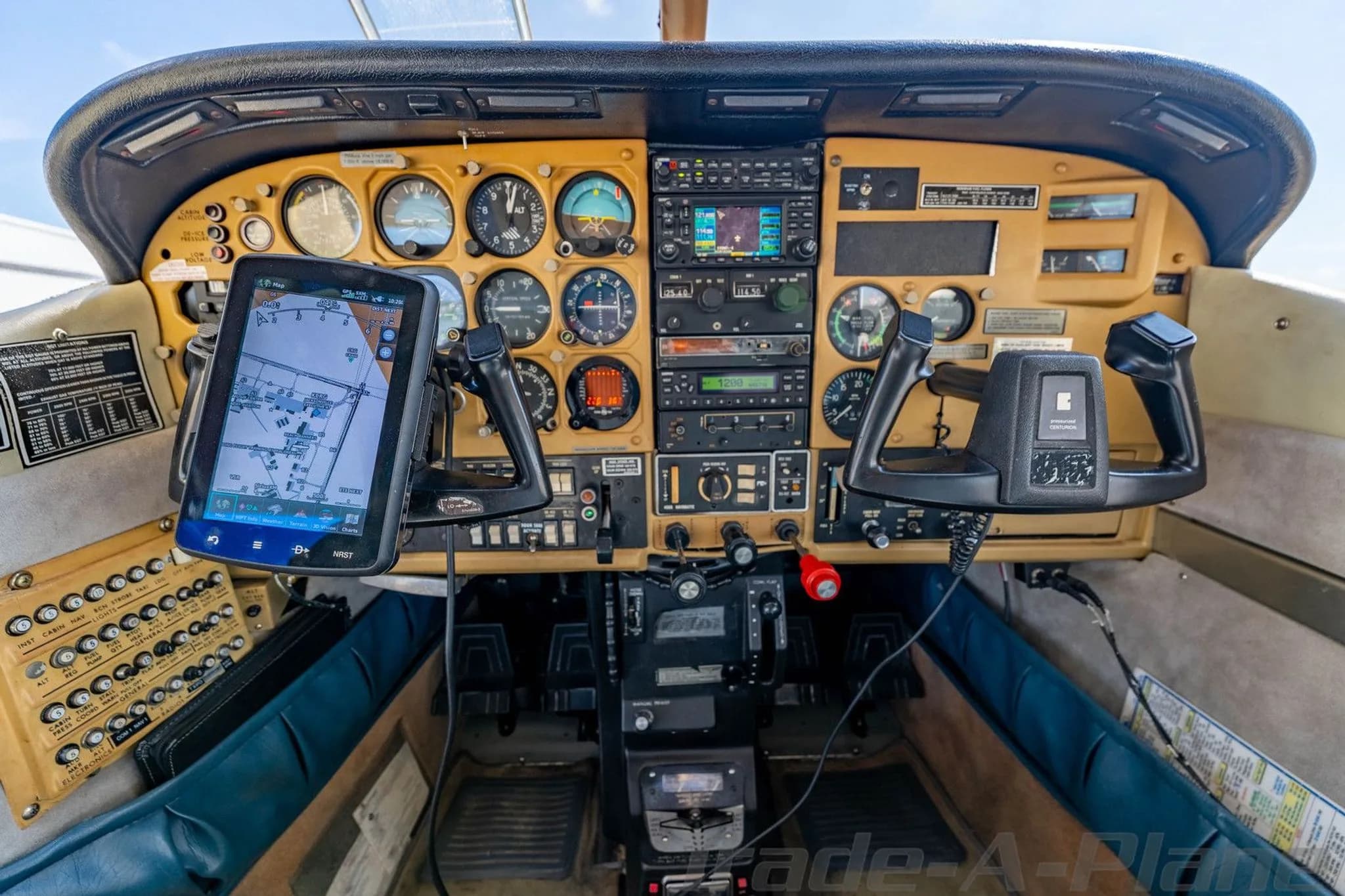 The aircraft's cockpit features a tan instrument panel with analog gauges, avionics, and a mounted tablet.
