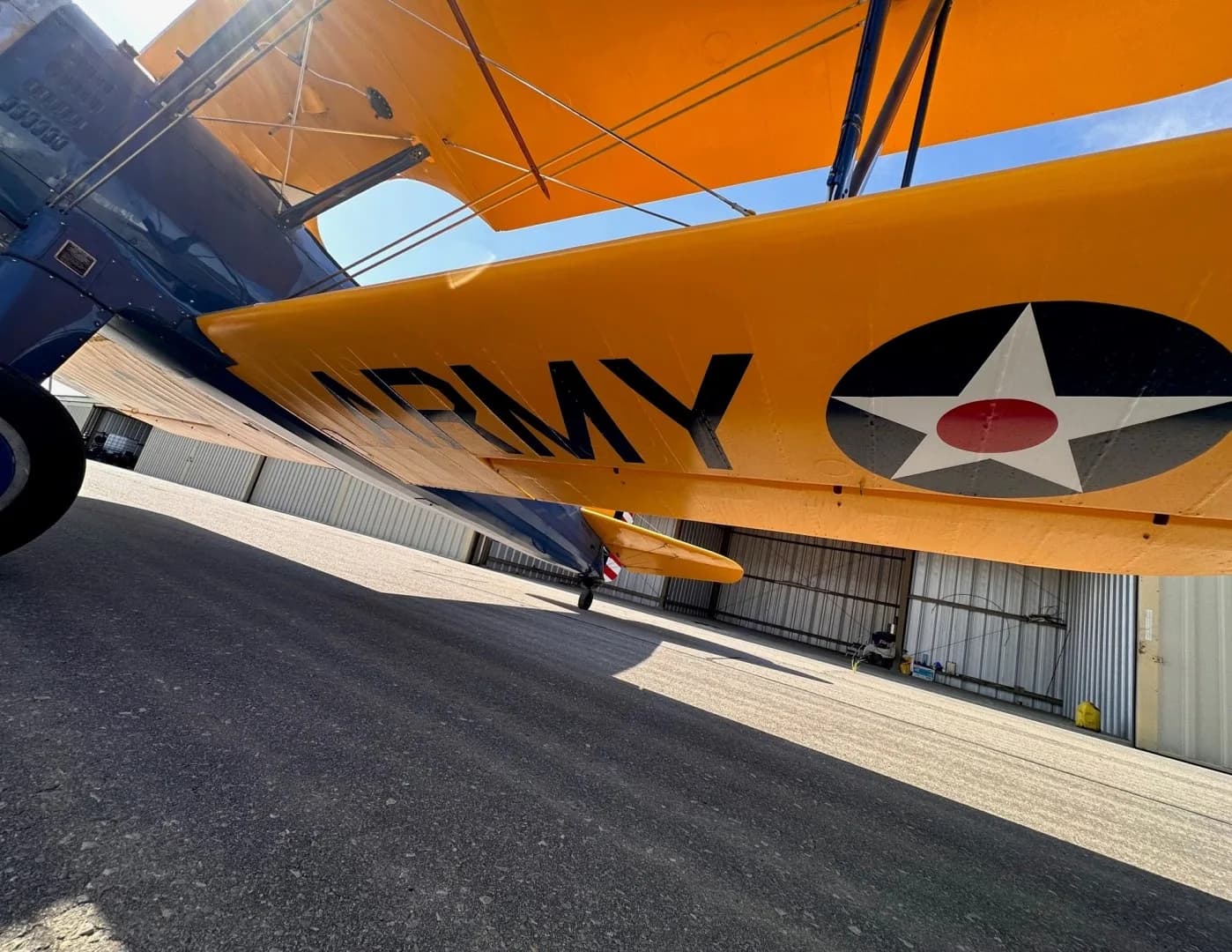 A close-up view of the underside of a yellow biplane wing, showing "ARMY" text and a US military star insignia.