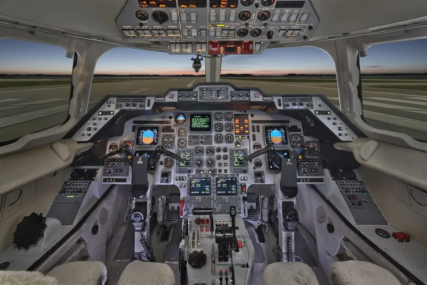 The cockpit of a business jet, featuring a complex instrument panel with multiple screens and controls, viewed from the pilot's seat.