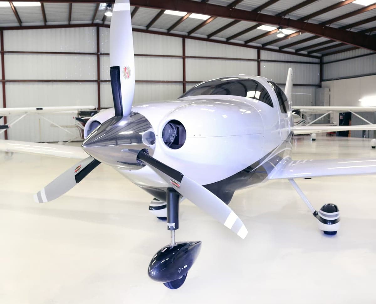 A Cirrus SR22T aircraft with registration N974MH is parked inside a hangar.