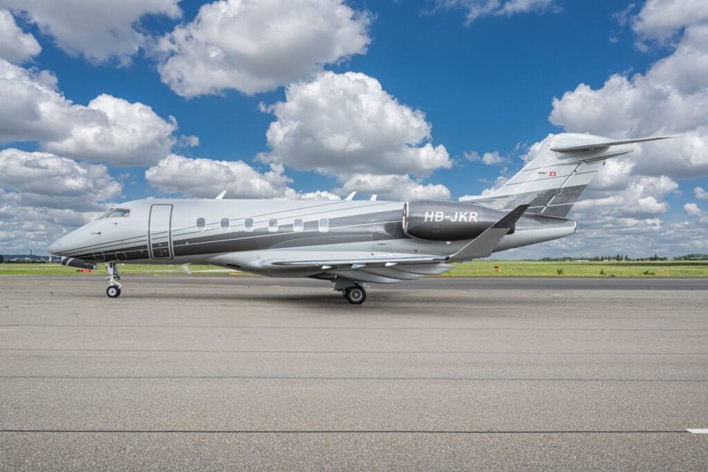 A Challenger aircraft with registration HB-JKR is parked on the tarmac.