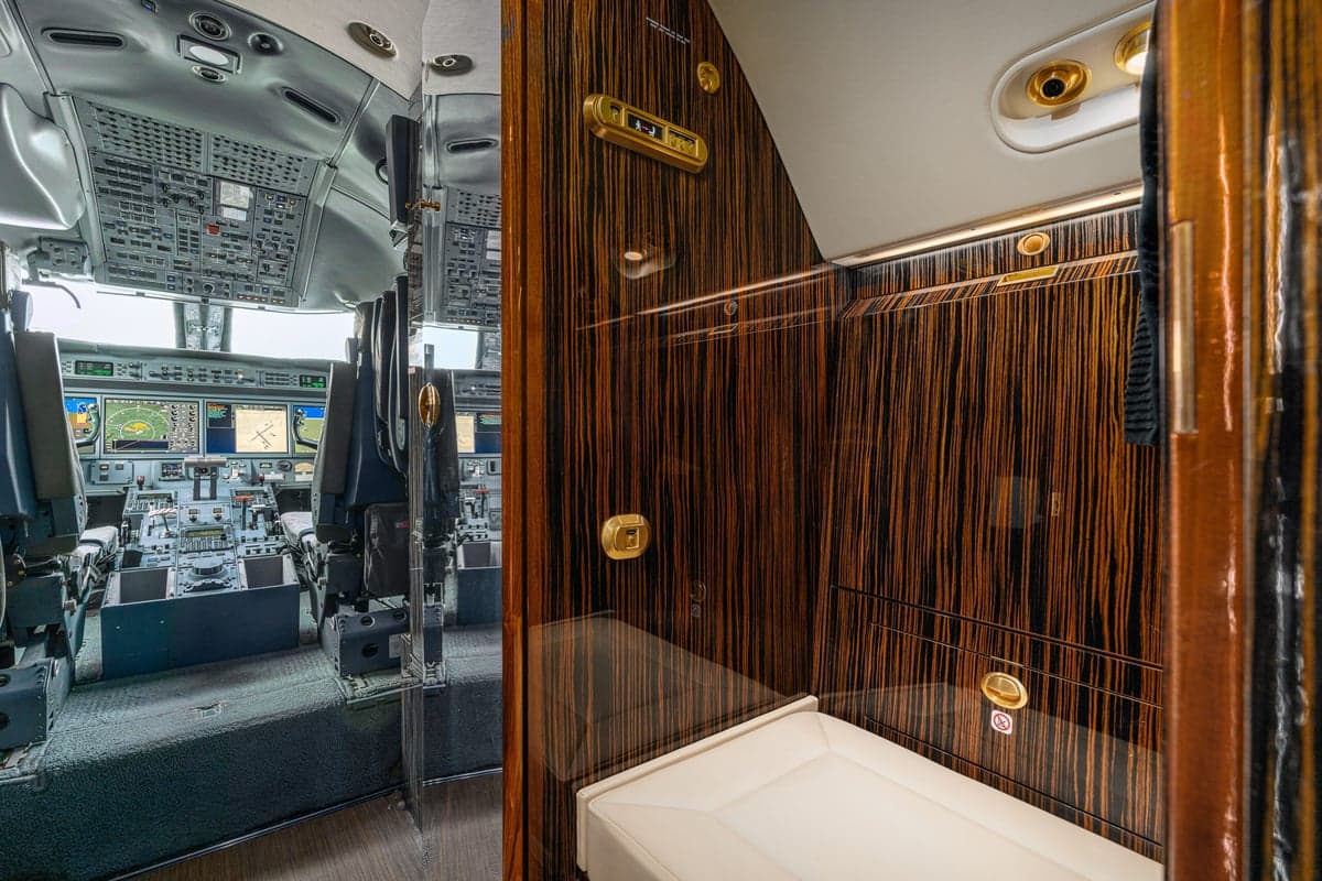 View of the cockpit and a lavatory with wood grain finishings.