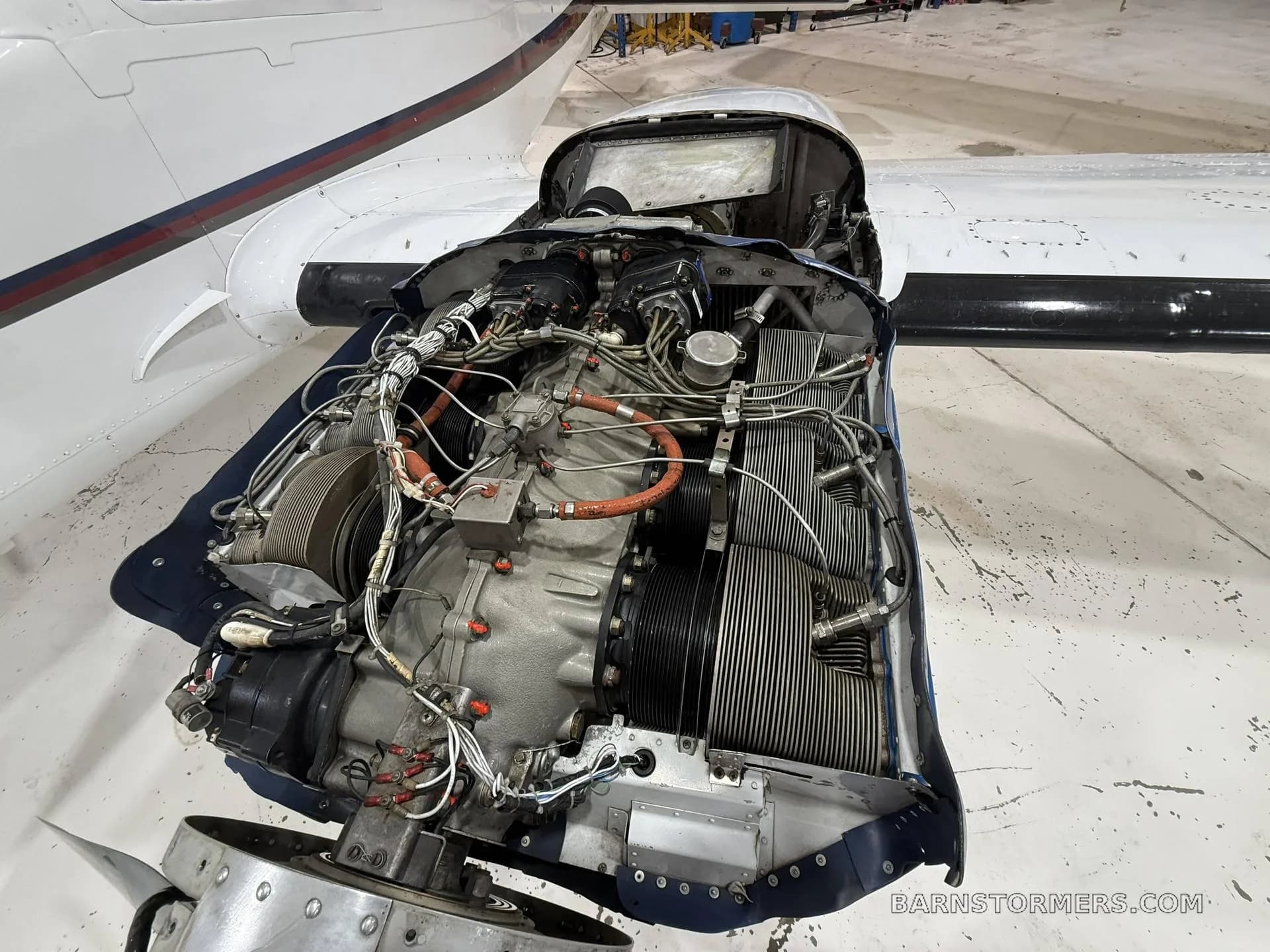 An overhead view of a Continental aircraft engine with its cowling removed, revealing internal components, in a hangar.