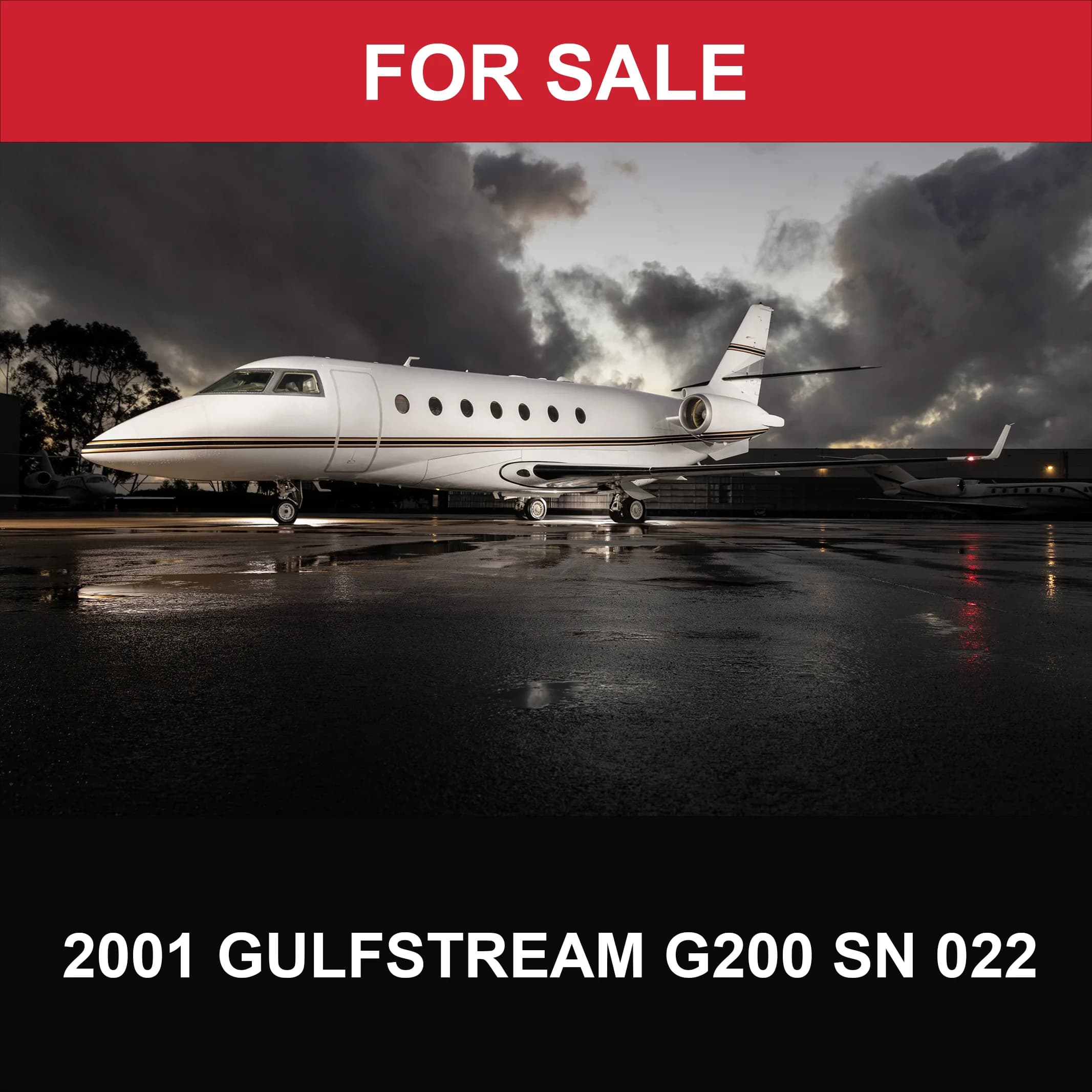 A white 2001 Gulfstream G200 business jet with a gold stripe is parked on a wet tarmac at dusk.