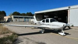 A Cirrus SR22 G3 aircraft with registration F-HMCJ parked in front of a hangar.