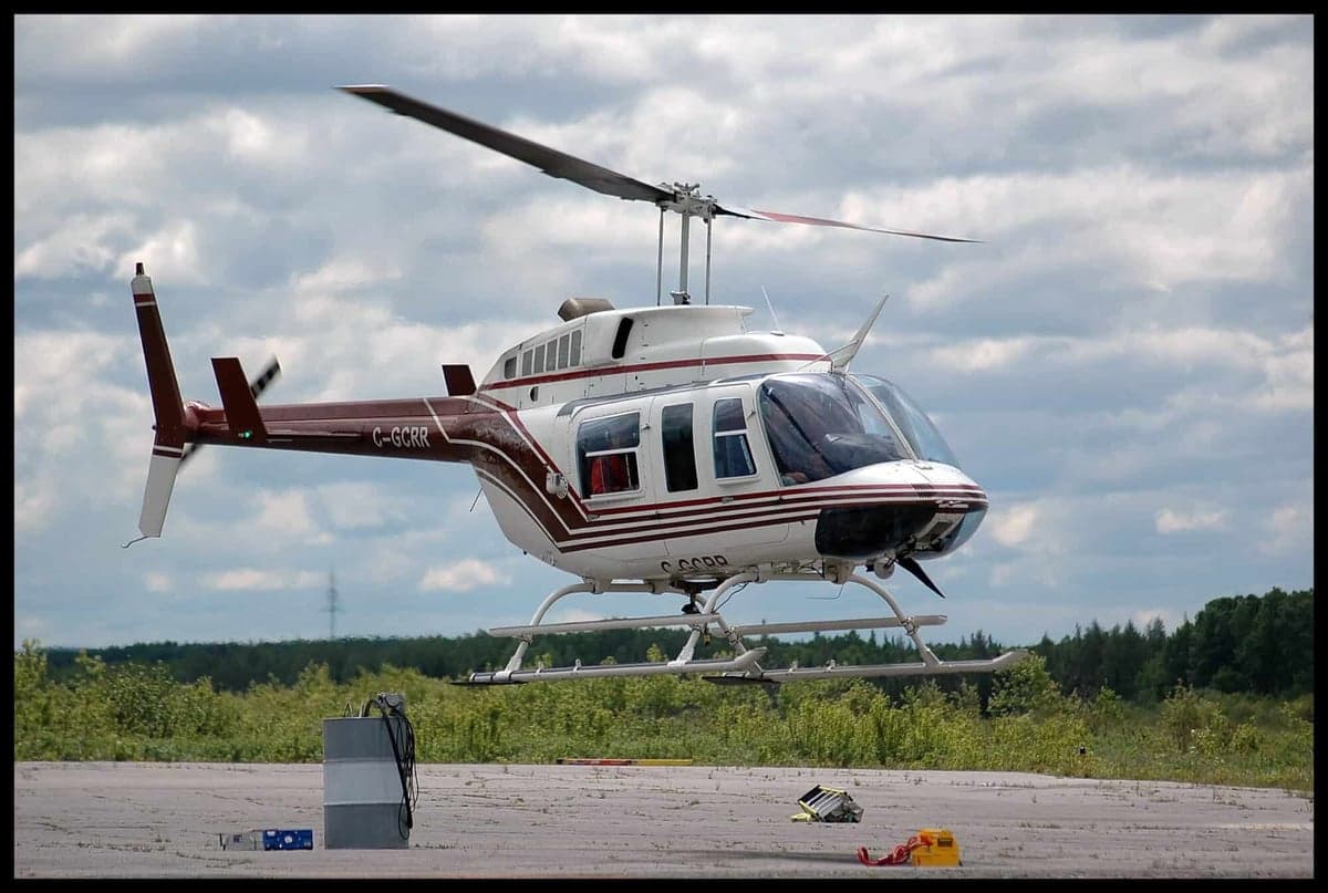 A Bell 206L-4 LongRanger helicopter taking off from a helipad.