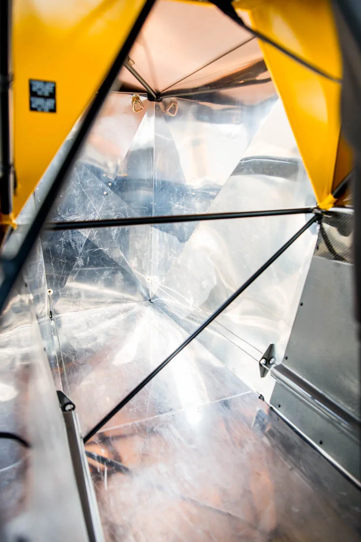 The spacious baggage compartment of a Carbon Cub aircraft features shiny metal walls and structural bracing.