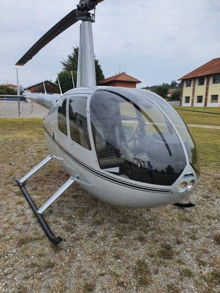Front view of a silver Robinson helicopter on the ground.