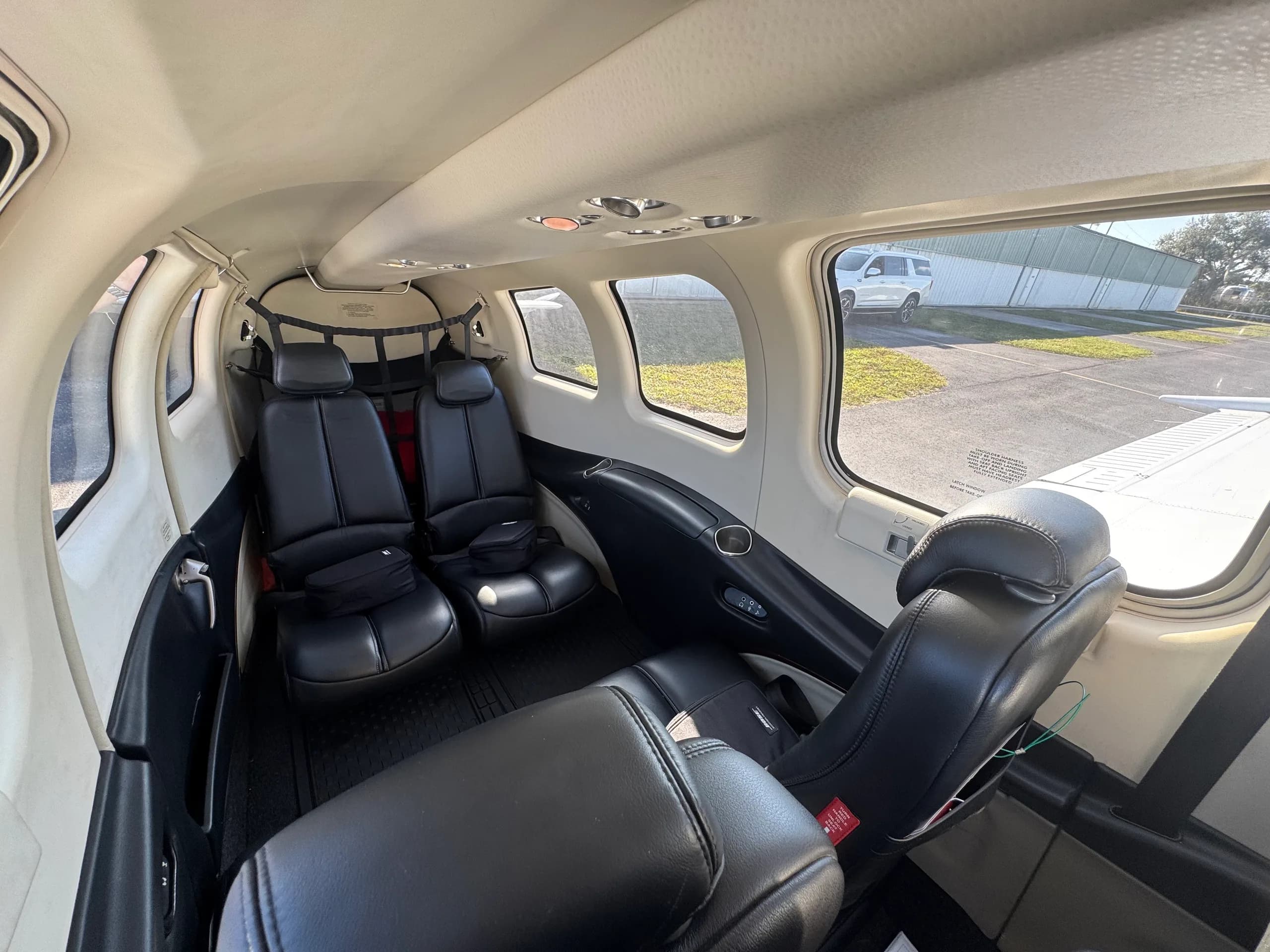 The full interior cabin of a Beechcraft Bonanza, featuring black leather seats and light-colored trim.