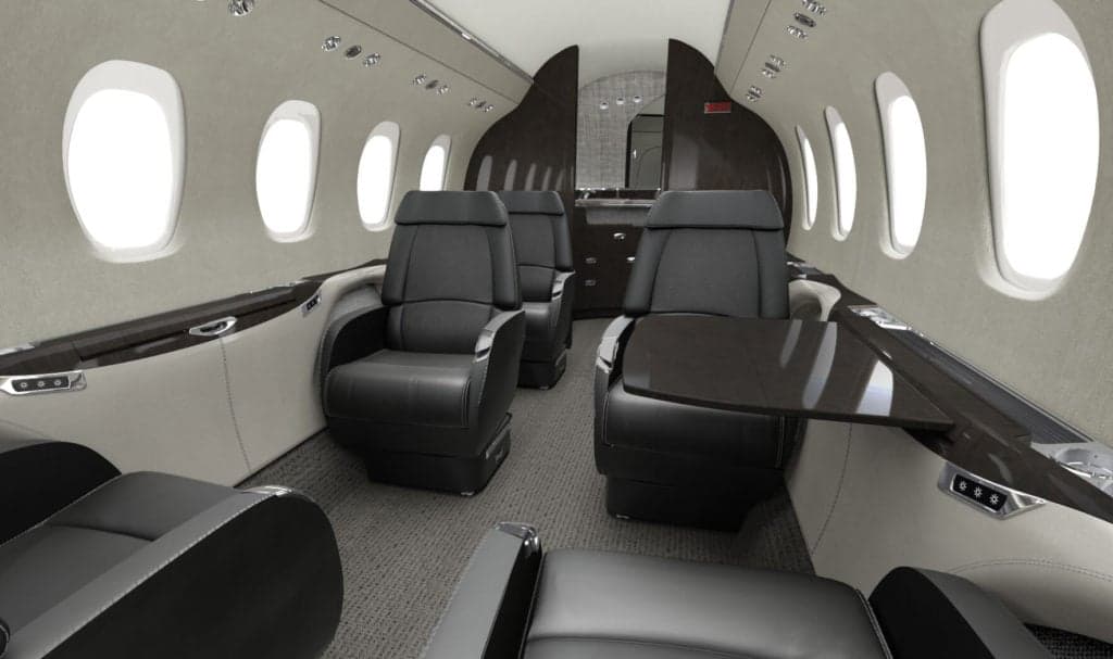 A view of the Citation Latitude cabin with black leather seats and wood trim.