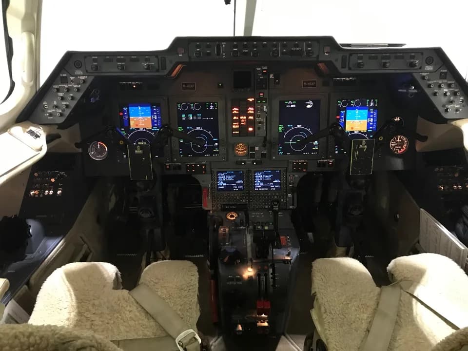 View of the aircraft's cockpit with instrument panel and sheepskin seat covers.