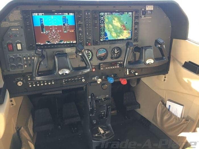 The instrument panel of the aircraft with dual screens and flight controls, with a Trade-A-Plane watermark.