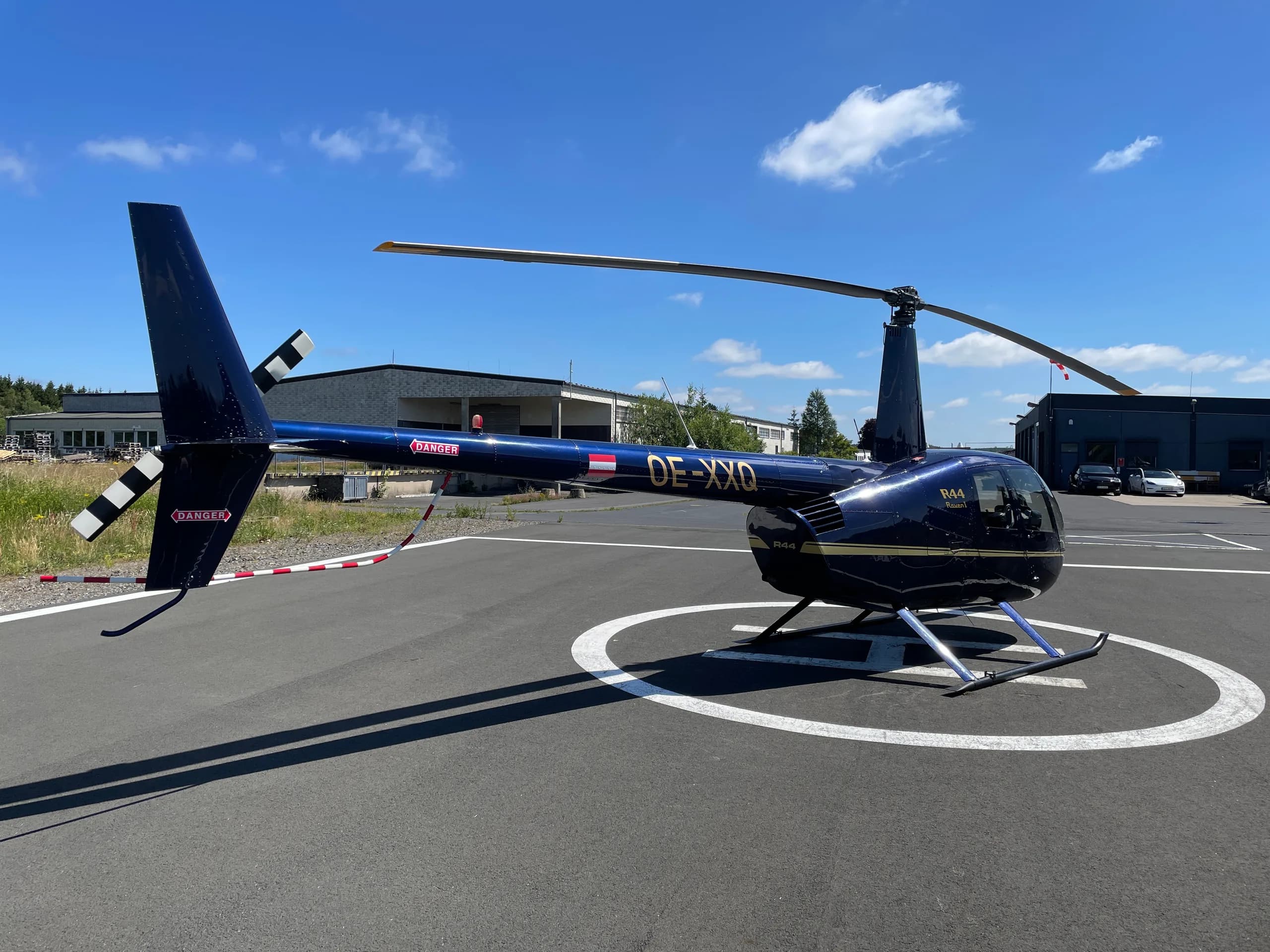 Robinson R44 Raven I OE-XXQ helicopter on a helipad.