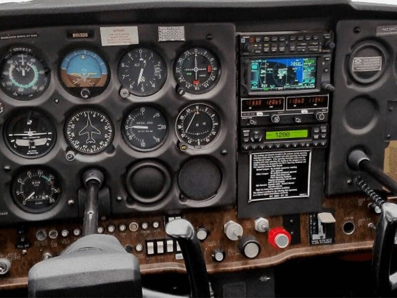 A close-up view of a general aviation aircraft cockpit with analog gauges and a modern GPS display.