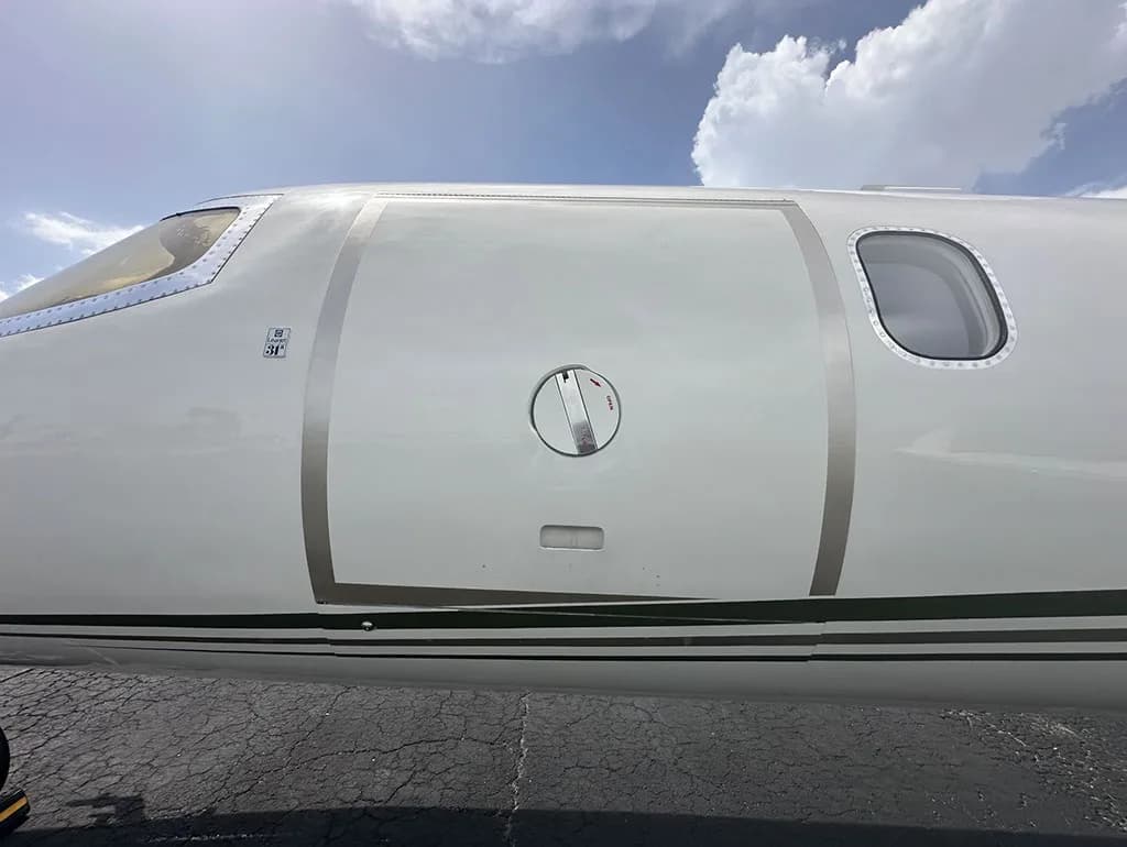 A very close-up view of the mid-fuselage of a white Learjet 35A, showing the entry door and fuel port.