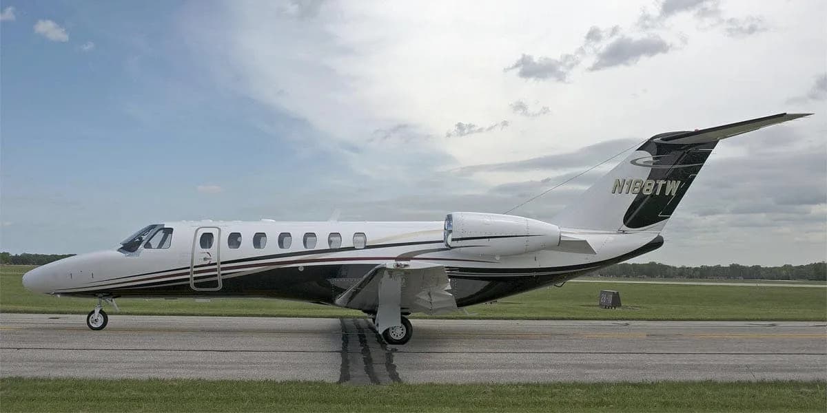A white and black business jet with registration N188TW on the tail, parked on a tarmac under a cloudy sky.