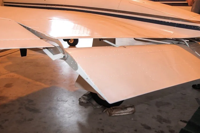 A close-up view of the underside of the wing and extended flaps of a white Cessna 421 Golden Eagle.