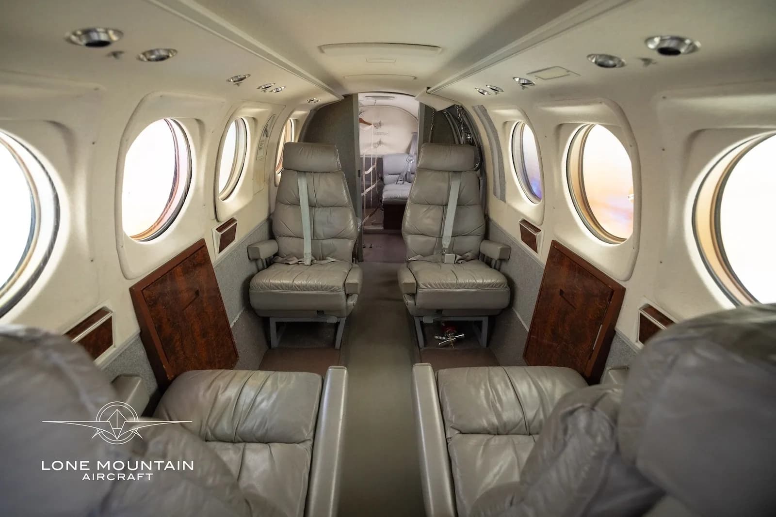 The aircraft's interior cabin features grey leather seats, looking towards the rear of the aircraft.