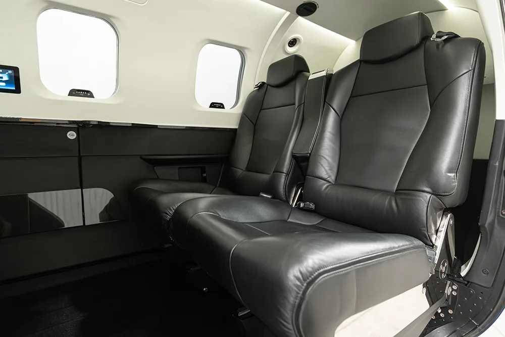 Close-up of two black leather passenger seats in a private jet cabin.