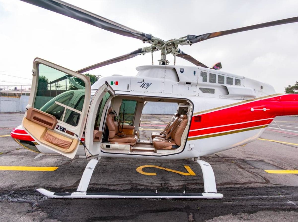 Side view of a Bell 407 helicopter with the doors open, showing the interior.