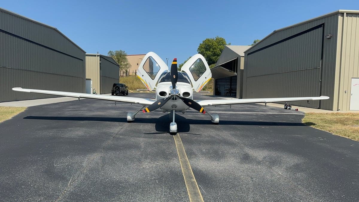 Front view of a Cirrus aircraft with its doors open on the tarmac.