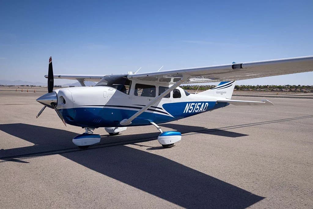 A three-quarter front view of a white and blue Cessna Stationair N515AD on an airfield.