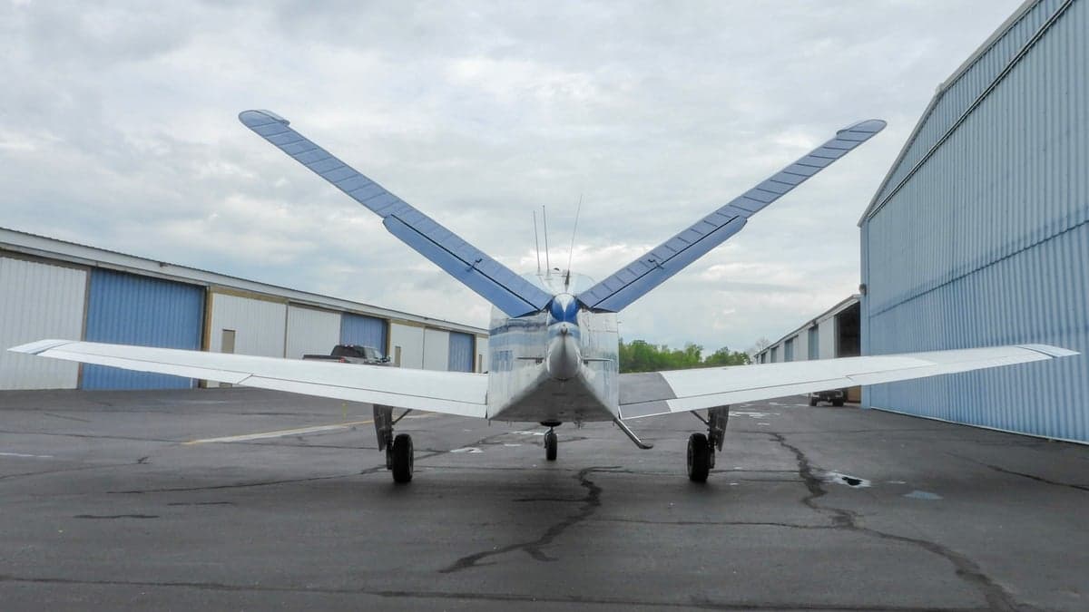 Rear view of a white and blue Beechcraft Bonanza parked on the tarmac.