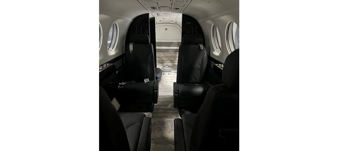 View of the aircraft interior showing the black leather seats and carpeted floor.