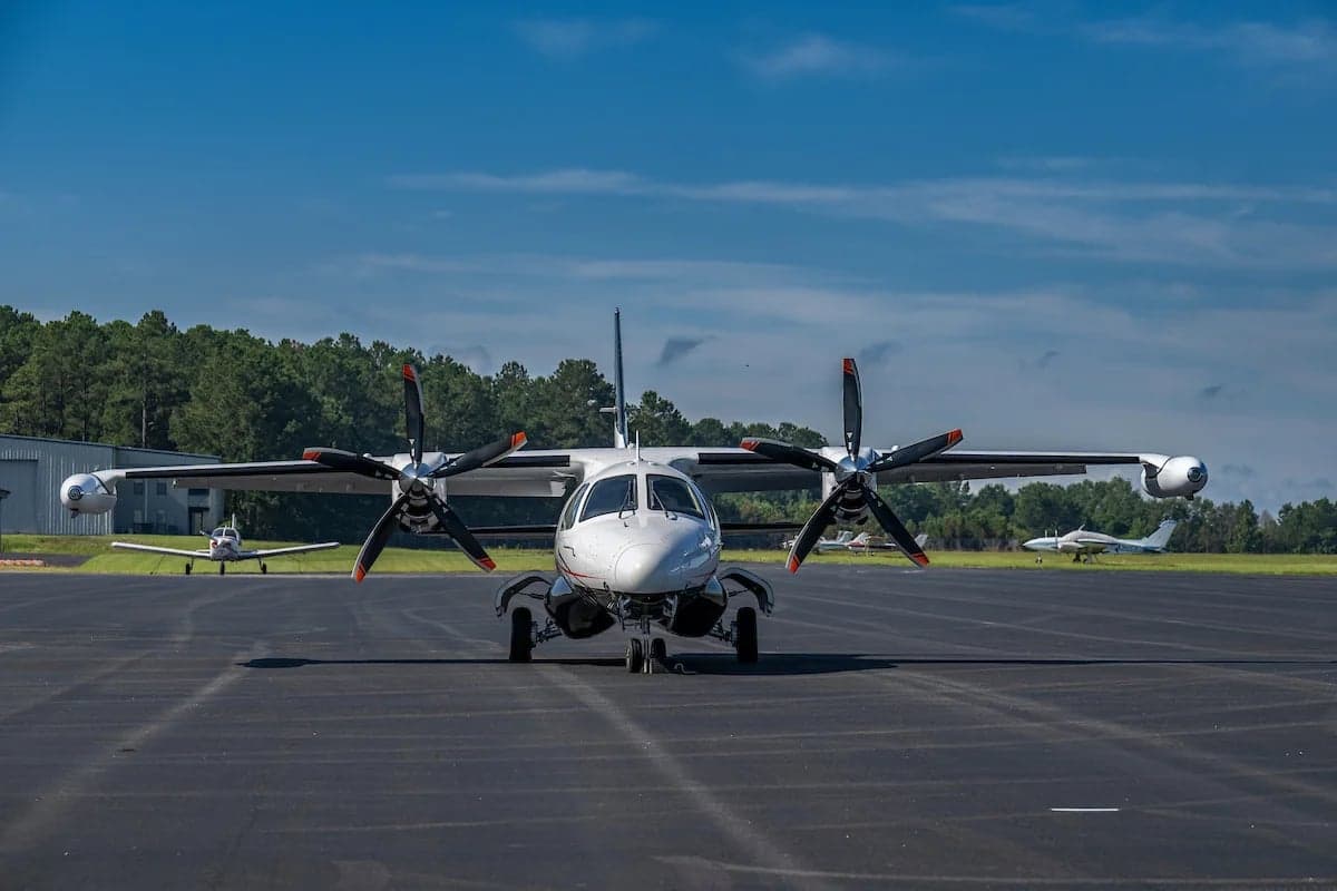 Front view of the N33EW aircraft on the tarmac with other aircraft in the background.