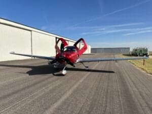 Front view of a Cirrus SR22T aircraft with its doors open on a tarmac.