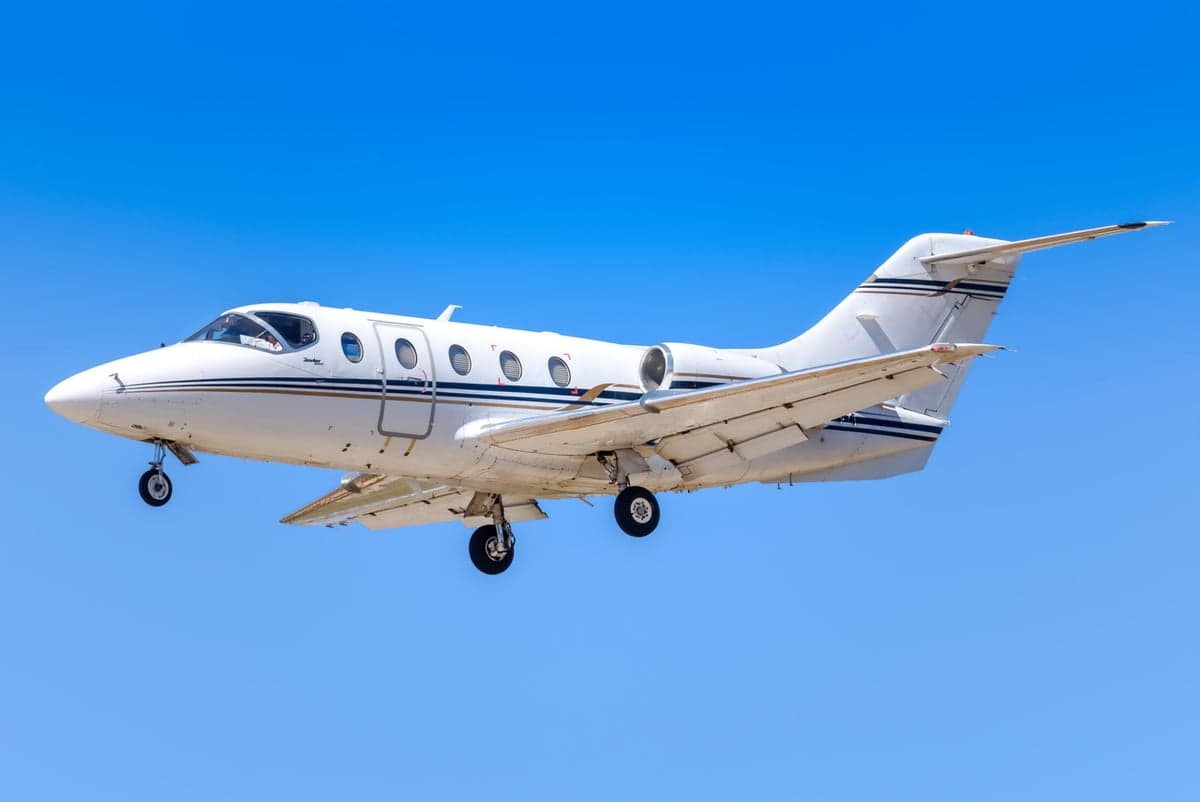 A white jet aircraft landing against a blue sky.