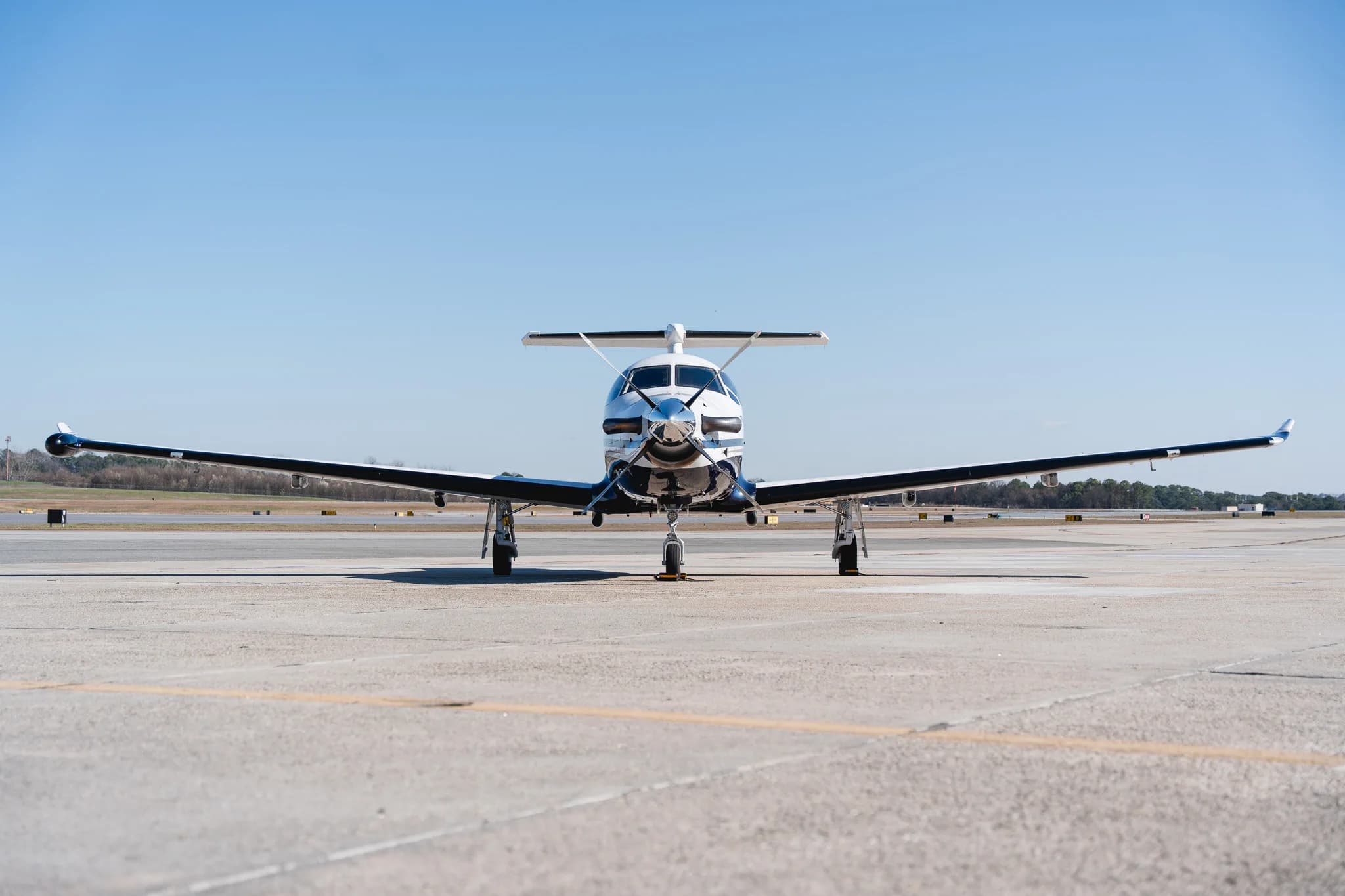 A head-on view of the Pilatus PC-12 turboprop aircraft, registration N133PE, with its propeller visible, parked on an airfield.
