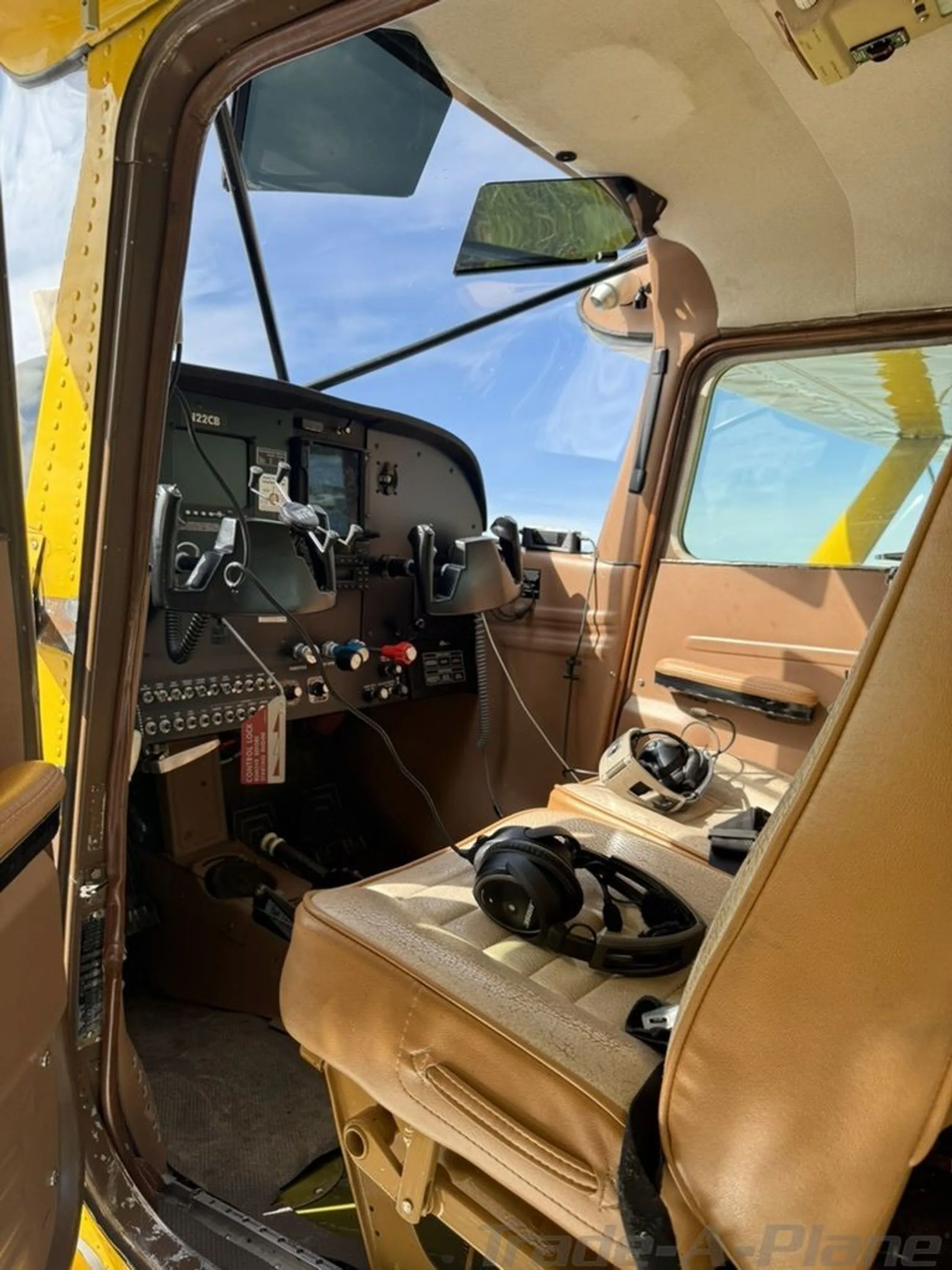 The tan interior of N22CB shows a pilot's seat with headphones and a view towards the cockpit.
