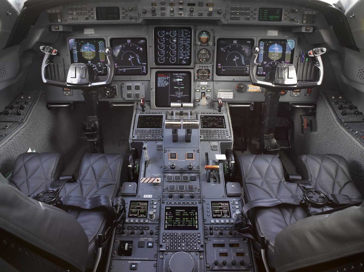 A wide view of the Gulfstream G650 cockpit, showing the pilot and co-pilot seats, instrument panels, and controls.