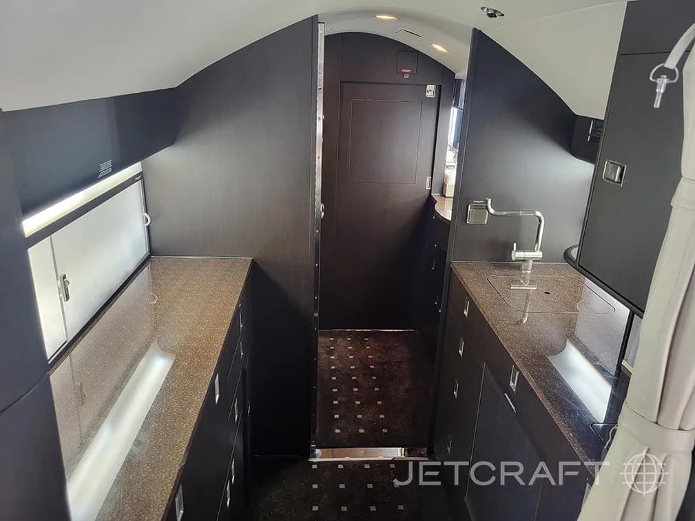 The aircraft galley with dark wood cabinetry, a sink, and ample counter space.