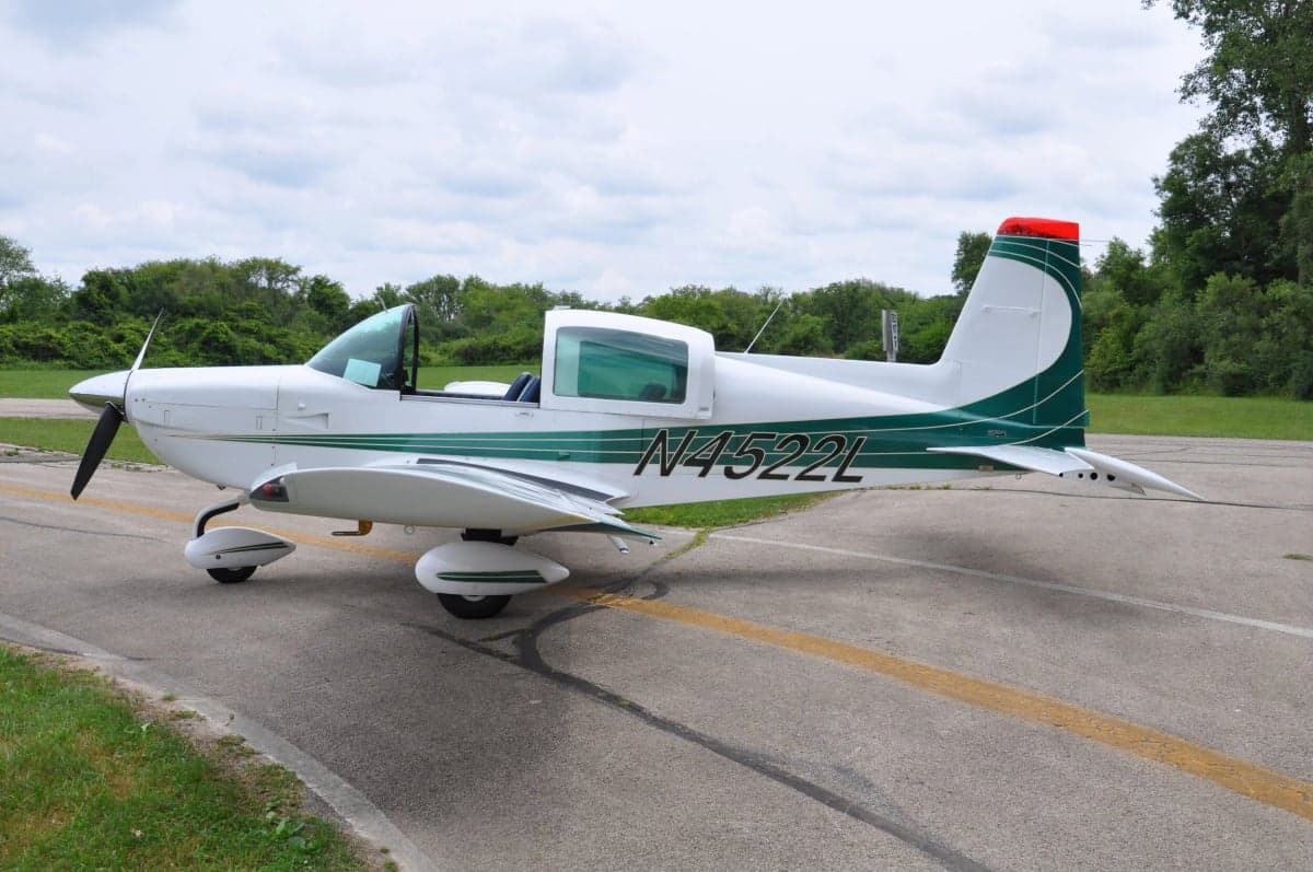 Side view of a white and green aircraft on the tarmac.