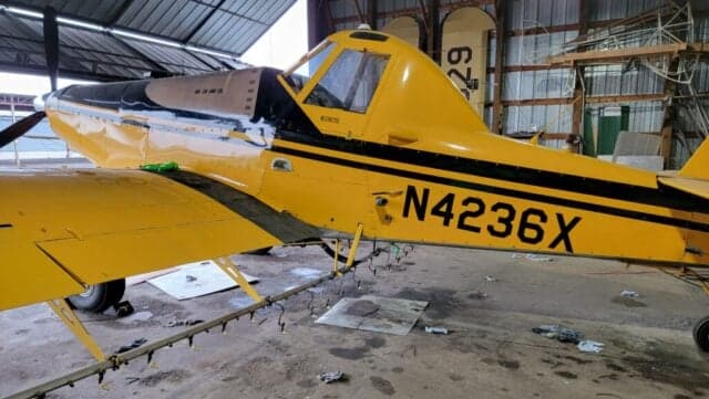 A yellow and black Air Tractor AT-400 sits inside a hangar.