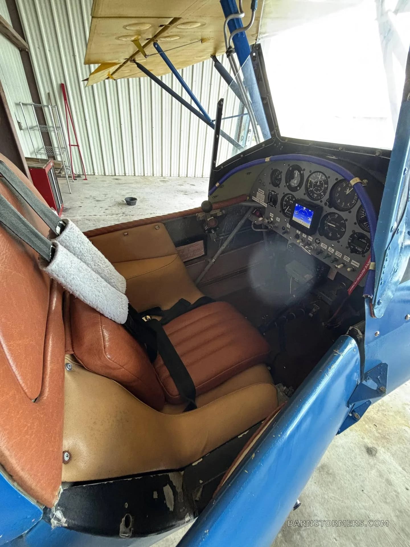 The brown leather seat and instrument panel of a single-seat aircraft's cockpit.