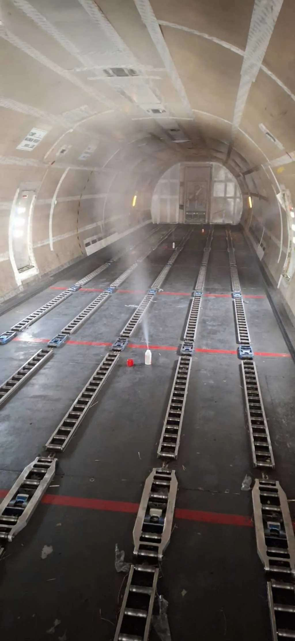The empty cargo hold of an aircraft, showing roller tracks and tie-down points on the floor.