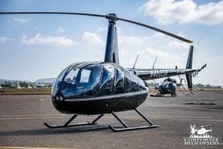 Robinson R44 helicopter on the tarmac with a black paint scheme.