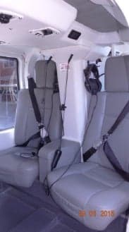 The interior of the helicopter with grey seats and headsets.