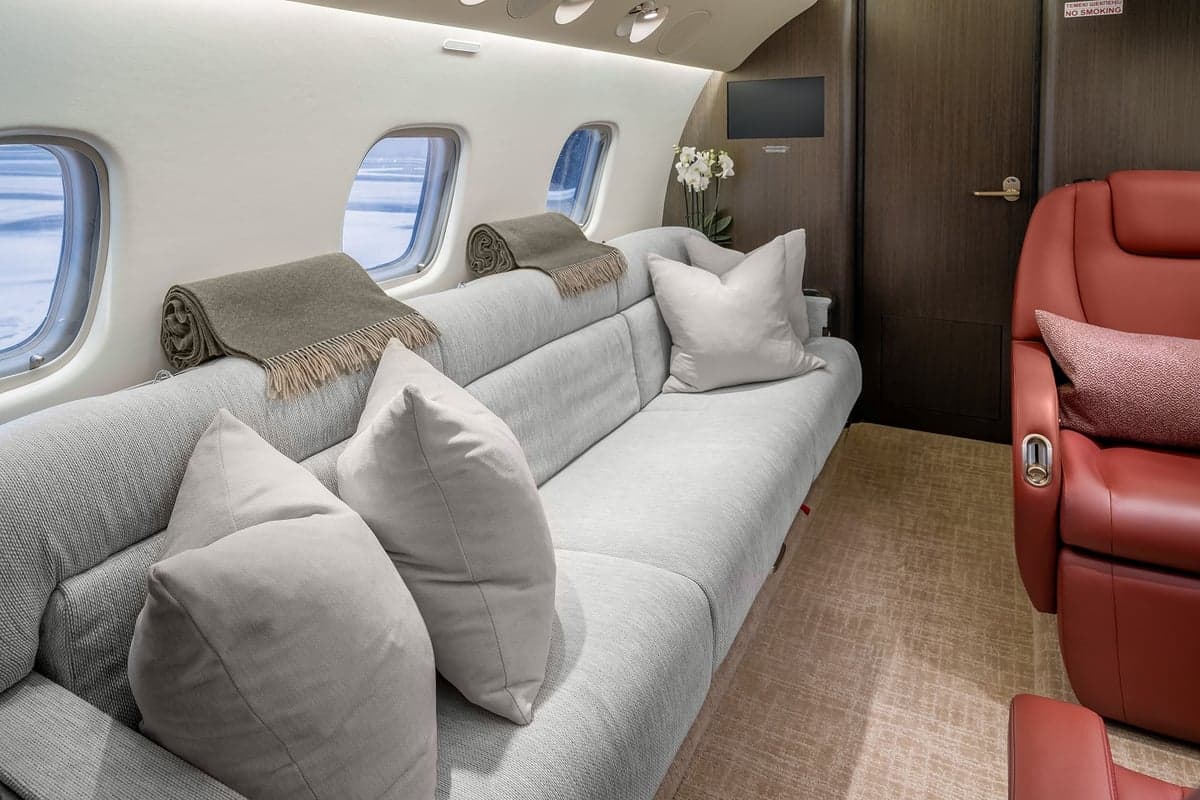 View of the aircraft interior with a couch and a neutral color scheme.