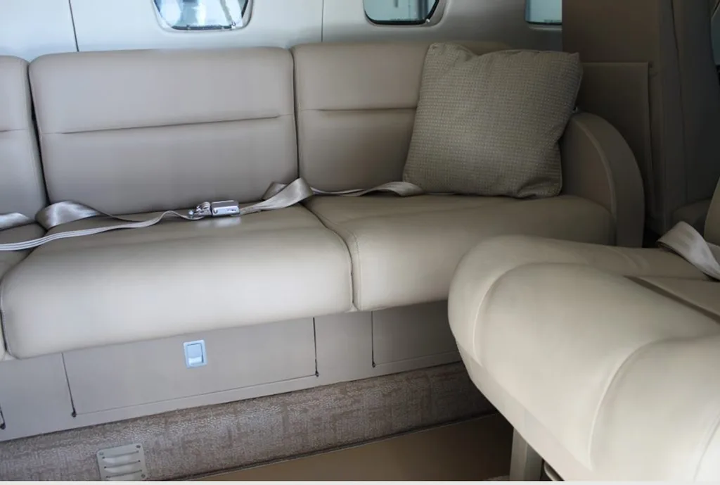 A close-up of the beige leather side couch in the aircraft cabin.