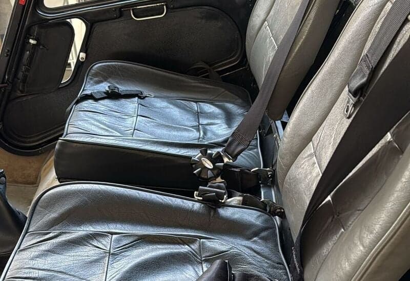 View of the black and gray leather seats in the cabin of a Robinson R44 helicopter.